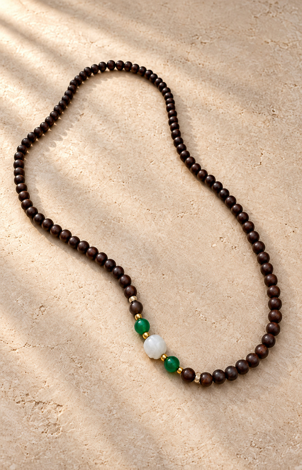 Between Shadows — dark brown beaded strand with green and white accents