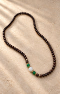 Between Shadows — dark brown beaded strand with green and white accents