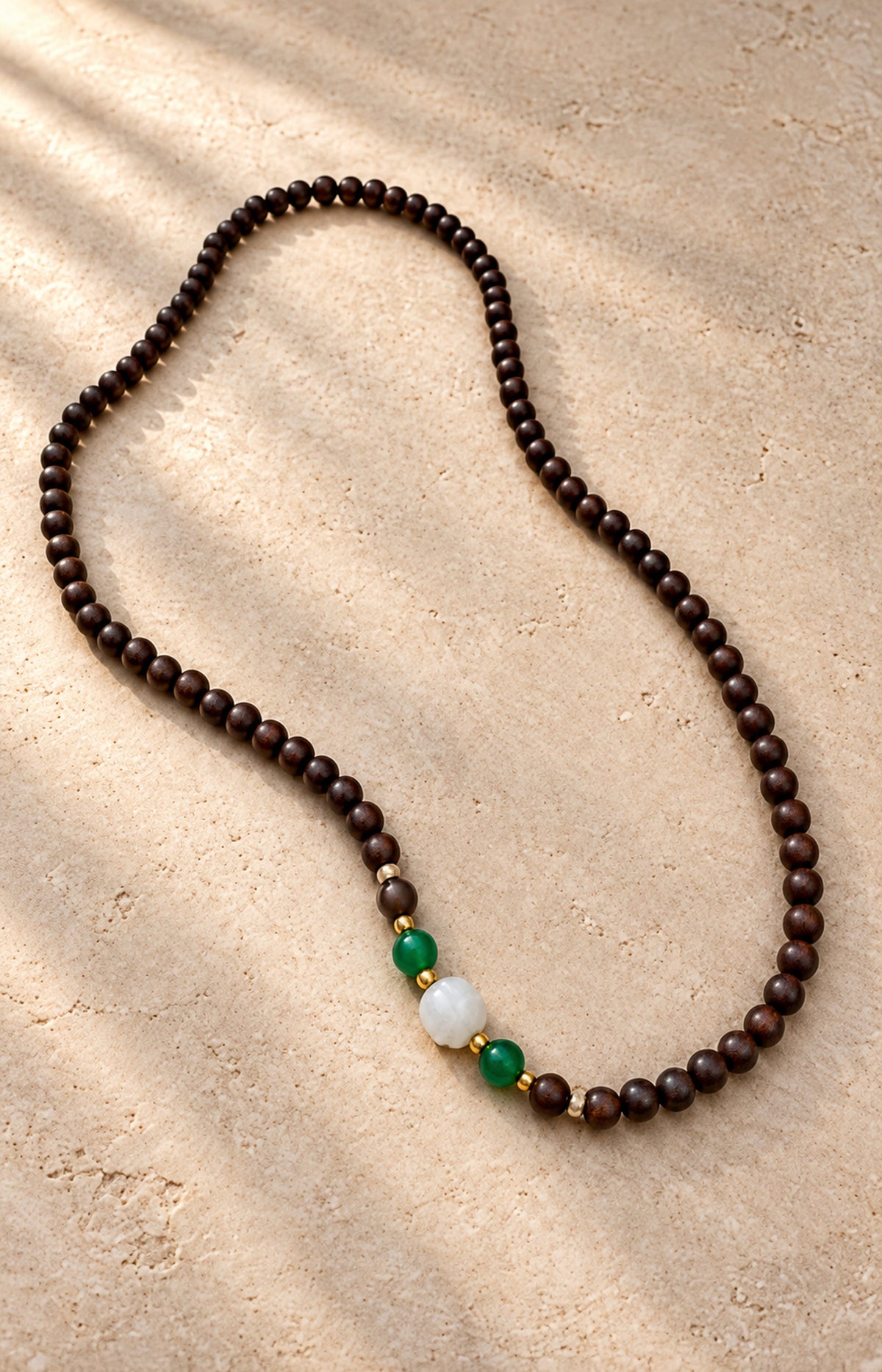 Between Shadows — dark brown beaded strand with green and white accents