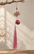 Pink charm suspended from a branch